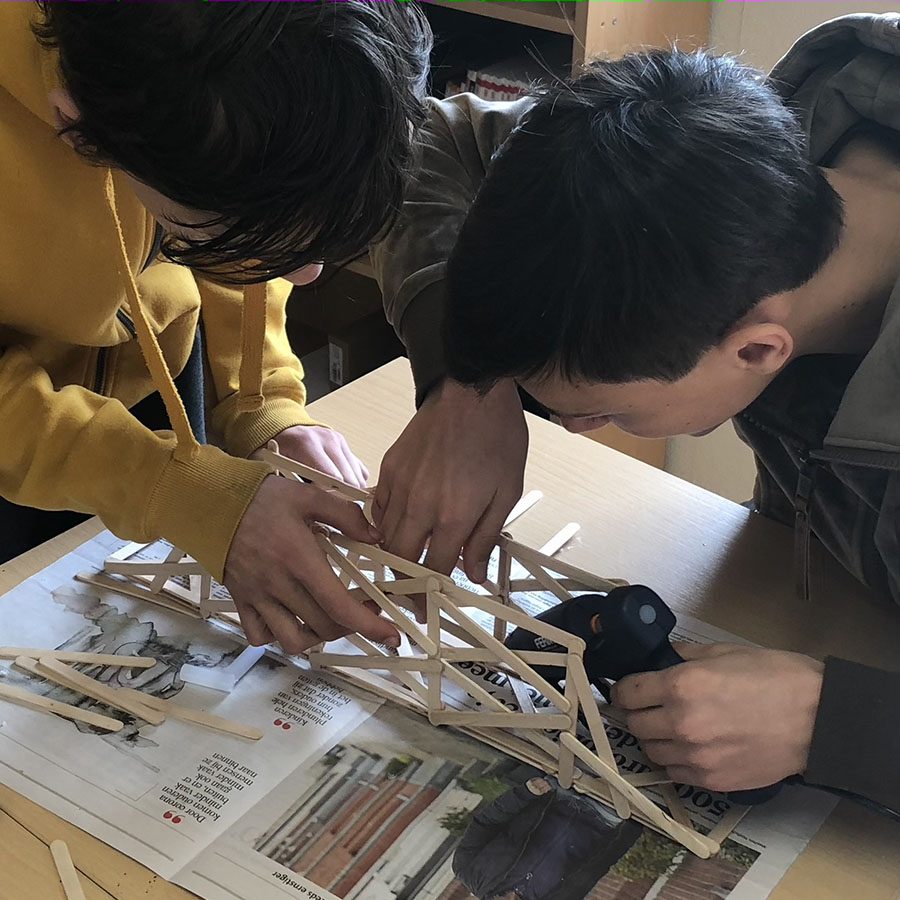 Students build a bridge of sticks together
