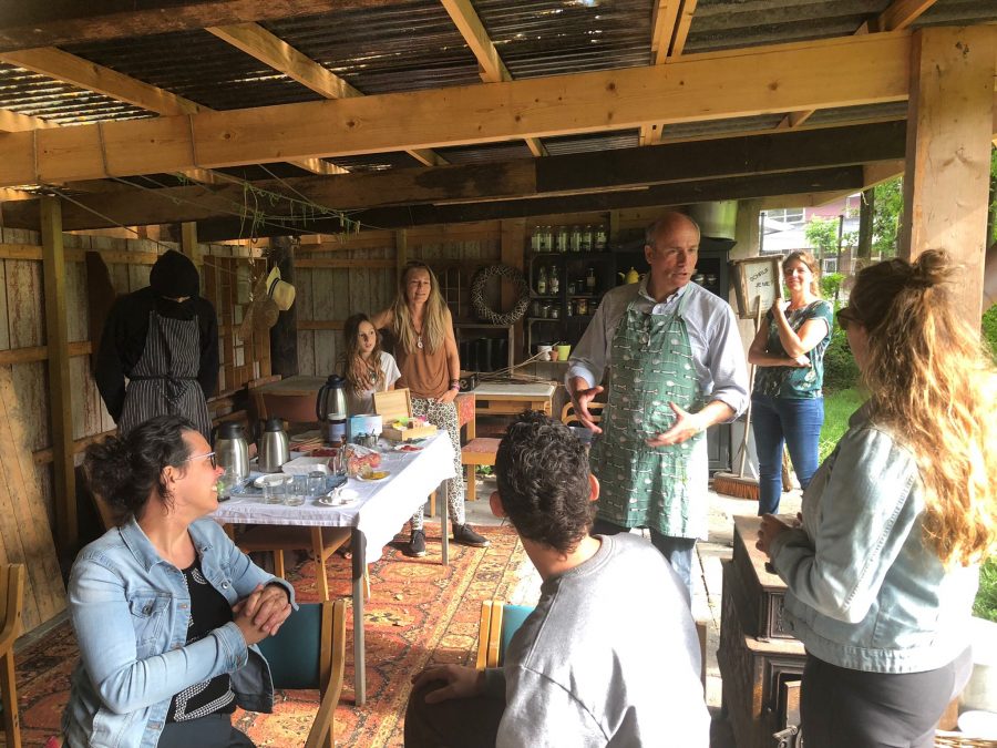 Parents are sitting and standing under a wooden roof.