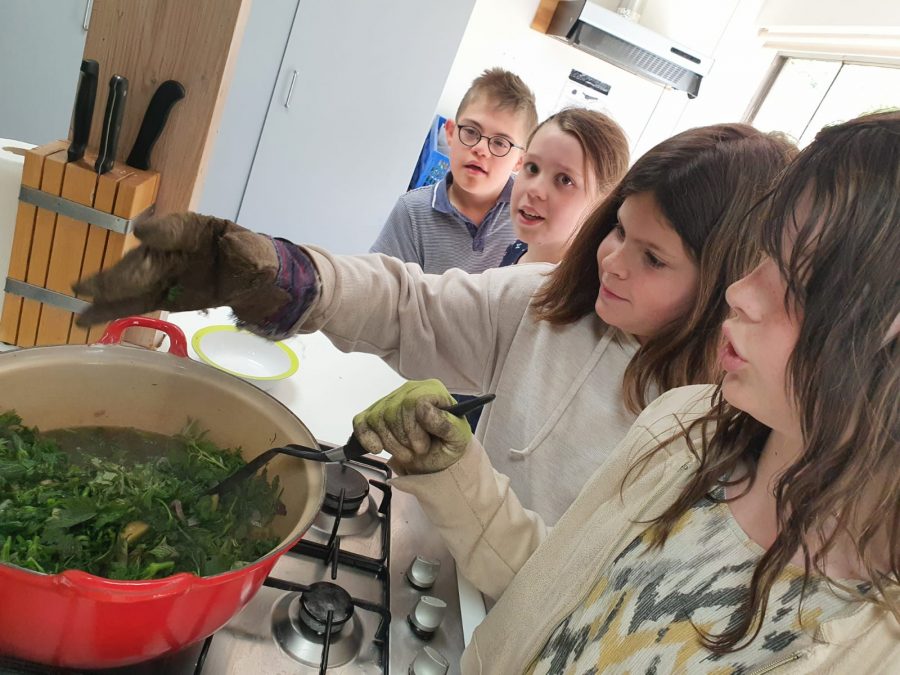 Four pupils are standing at a stove, two of them are making nettle soup