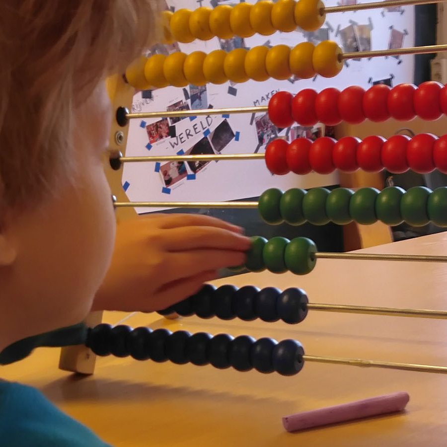 A pupil touches a wooden calculator rack with coloured balls
