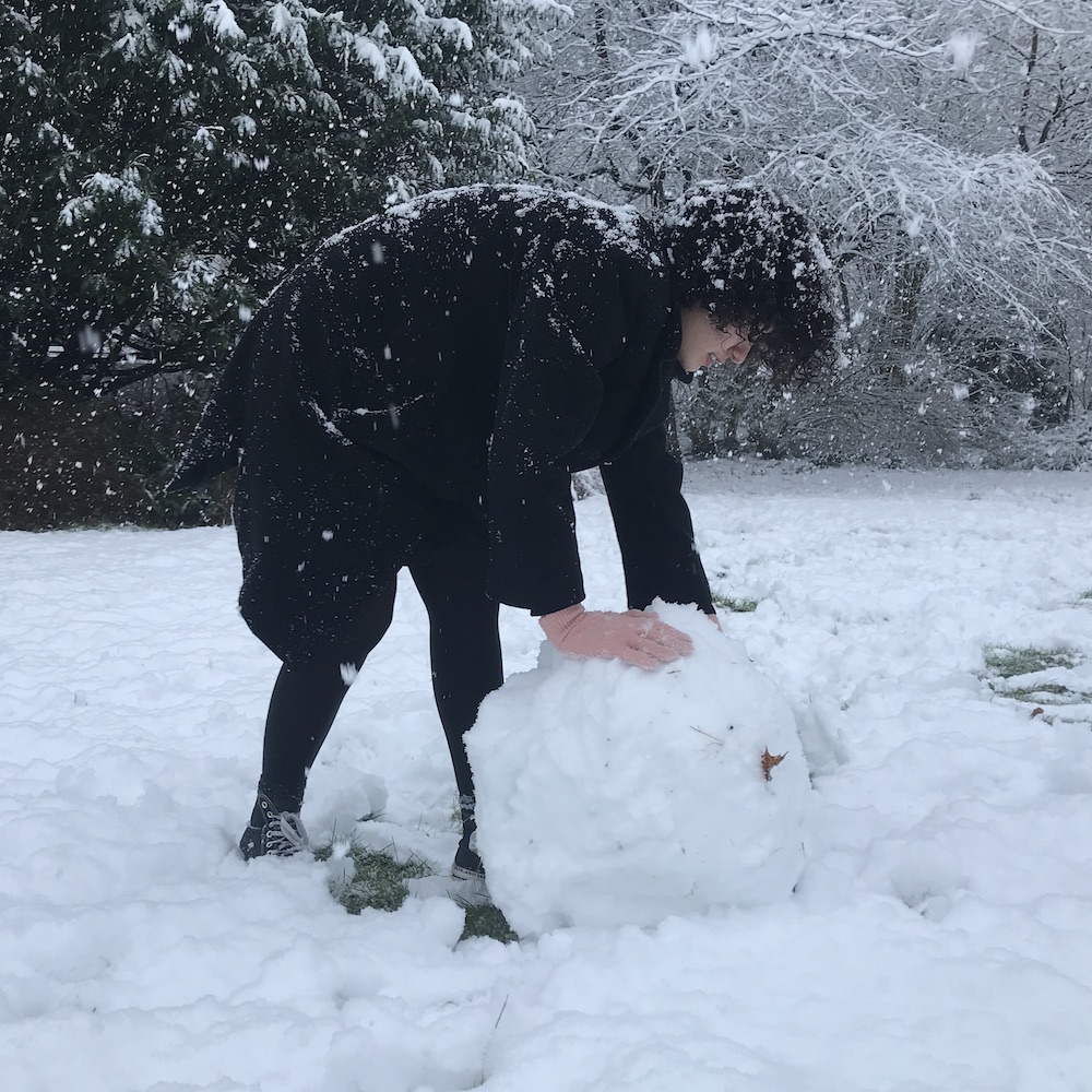Een student rolt een grote bal sneeuw