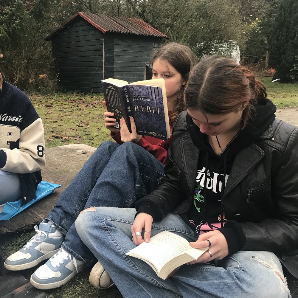 Twee studenten lezen bij het kampvuur
