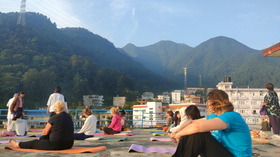 Deelnemers van IDEC Nepal zitten op matjes op het dak van een gebouw, met uitzicht op de bergen.