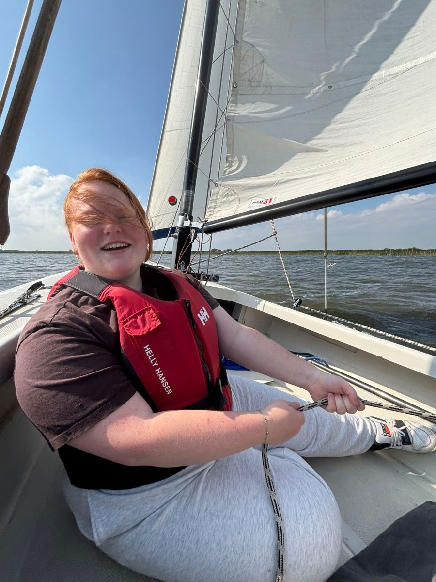 Student Saar zit op een zeilboot en zet zich schrap tegen de zijkant van de zeilboot.