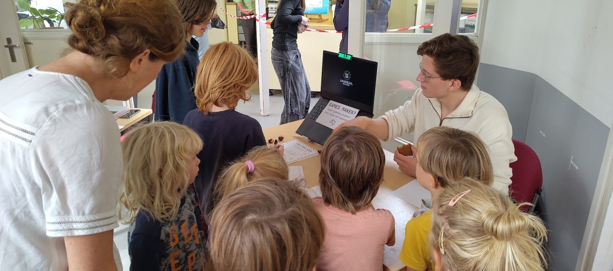 Jonge studenten staan bij een tafel, docent Julian helpt ze bij het inschrijven voor zijn lessen Game Design, op democratische school De Ruimte in Soest.